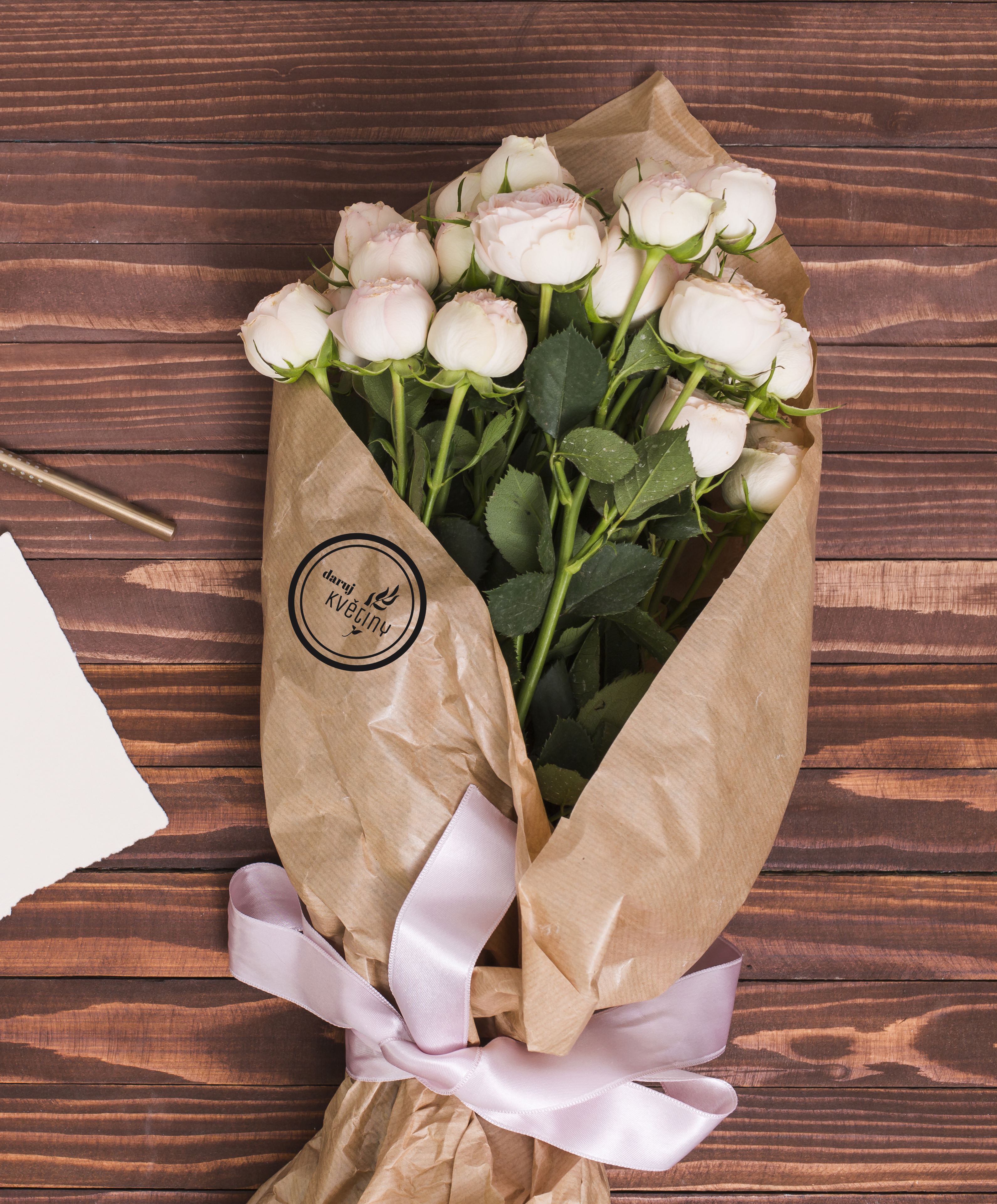 Bouquet of flowers wrapped in brown recycled paper with a print of the logo. 